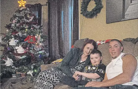  ?? CHRIS YOUNG THE CANADIAN PRESS ?? Evan Leversage, centre, sits in his family home with mother Nicole Wellwood, left, and father Travis Leversage before watching a Christmas Parade in St. George, Ont., on Oct. 24, 2015. The village came together to throw Evan, who was terminally ill...