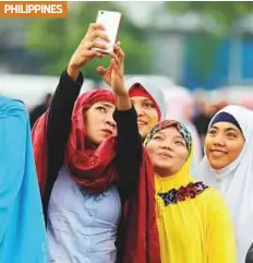  ?? Reuters ?? Filipino Muslims take a selfie during the first day of Eid before morning prayers at a park in Manila.