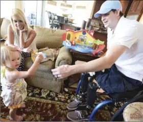  ??  ?? In this AprIl 1, 2015, file photo, retired Air Force Airman Brian Kolfage (right) gives a piece of cheese to his 1-year-old daughter Paris Kolfage as his wife Ashley Kolfage looks on at their recently rented home in Sandestin, Fla. NICK TOMECEK/NORTHWEST