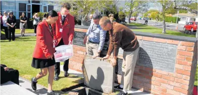  ?? ?? Head girl Te Otiana Gerrard and head boy Matthew Jones place a time capsule in the ground with the help of Brad Gibbons and his son Daniel.