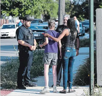  ?? MAX ORTIZ THE ASSOCIATED PRESS ?? Deborah Golden, center, talks with Detroit police after she tried to render aid to a young girl who later died of her injuries in Detroit on Monday. Police say the owner of three dogs is in custody after the animals killed Emma Hernandez, 9, as she rode a bike.