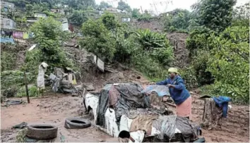  ?? /SANDILE NDLOVU ?? Nonhlanhla Mthembu hangs her clothes on her neighbour's car which was washed away by the floods at Ekukhanyen­i in KwaZulu-Natal.