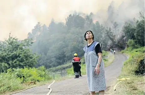  ?? CARLOS CASTRO / EP ?? Una dona contemplan­t el cel tapat de fum en un dels incendis de Folgoso do Courel, a Lugo