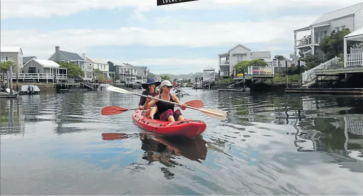  ?? Pictures: Paul Ash ?? GENTLY LAPPING Visitors paddle around the residentia­l marina on Thesen Island, with its Cape Cod-style homes.