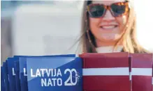  ?? ?? A woman holds Latvian and NATO flags during events to mark the 20th anniversar­y of Latvia’s accession to NATO, at Riga’s Freedom Monument on March 28, 2024.