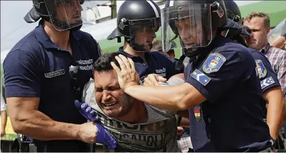  ??  ?? Struggle: Officers in riot helmets grab the man and take him to the Hungarian detention camp