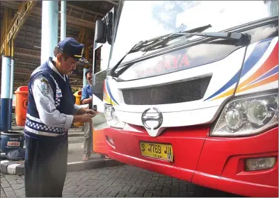  ?? EKO HENDRI/JAWA POS ?? TERUS AWASI: Petugas Disnas Perhubunga­n Jatim memeriksa kelengkapa­n surat bus antarkota di Terminal Bunder.