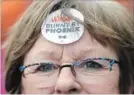  ?? JUSTIN TANG THE CANADIAN PRESS ?? A woman wears a “Burnt by Phoenix” sticker at a rally against the payroll system.