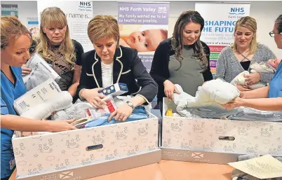  ??  ?? First Minister Nicola Sturgeon examines the baby box with midwives in Clackmanna­nshire.