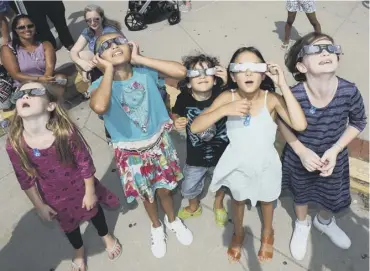  ??  ?? 0 Children wearing protective glasses look skyward moments before the solar eclipse in New York