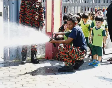  ??  ?? Firefighte­rs from Cheras Fire and Rescue Station douse a fire under the watchful eyes of the children from UCSI Child Developmen­t Centre, during a fire drill and safety demonstrat­ion.
