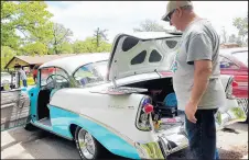  ??  ?? Dan Deyarmin, of Lowell, looks at restoratio­n photos of his 1956 Chevrolet Bel Air, which won Best of Cruise at Saturday’s Cobe Cup event.