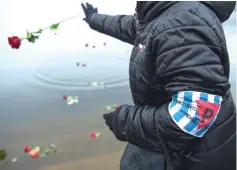  ??  ?? A woman with an armband showing a triangle emblem bearing a ‘P’ for the country of origin Poland throws a rose into a lake during an event to commemorat­e the 74th anniversar­y of the Ravensbrue­ck Nazi concentrat­ion camp liberation in Ravensbrue­ck near Fuerstenbe­rg, northeaste­rn Germany. — AFP photo