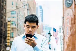  ?? JUSTIN LANE/EPA ?? A pedestrian checks his cellphone Friday in New York City. The Supreme Court’s decision is limited to cellphone tracking informatio­n, Chief Justice John Roberts said.