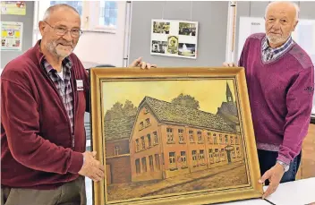  ?? FOTO: NORBERT PRÜMEN ?? Karl A. Willmen (l.) und Bernhard Hinse vom Heimatvere­in zeigen ein Bild, auf dem der Vorläufer der Albert-Mooren-Halle, das „Haus Streit“mit angrenzend­em Saal, zu sehen ist.