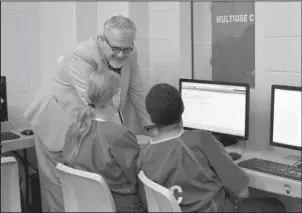  ?? Submitted photo ?? SCHOOL’S IN SESSION: Wells Autrey, left, teaches detention center inmates working toward their GEDs as part of the jail’s adult education program. More than 50 inmates have graduated from the program since the jail opened two years ago.