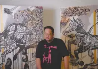  ??  ?? CARTOONIST Jose Santos P. Ardivilla stands next to two works he made for his MFA degree exhibit, Kahayupan.