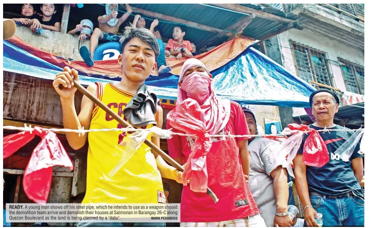  ?? MARK PERANDOS ?? READY. A young man shows off his steel pipe, which he intends to use as a weapon should the demolition team arrive and demolish their houses at Salmonan in Barangay 26-C along Quezon Boulevard as the land is being claimed by a "datu".