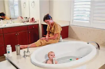  ?? ?? Geri Landman watches then-16-month-old Lucy play in the bathtub in September. On her good days, Lucy is cheerful and alert, and able to sit up on her own for long stretches.