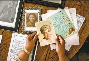  ?? Jason Armond Los Angeles Times ?? DENISE DIGGS holds a photograph of her late mother as she and her brother Richard Diggs sift through a table full of old family documents and pictures at home in Apple Valley, Calif.