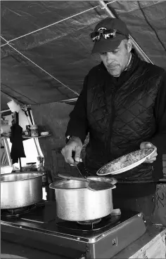  ??  ?? Perry whipping up food in a tent kitchen.