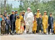  ??  ?? AFP Gulzar Khan, who has 36 children, walks with his children as they return home after school. —