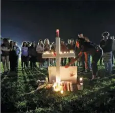  ?? AP PHOTO/GERALD HERBERT ?? A woman places a poster of shooting victim Meadow Pollack, at one of seventeen crosses, after a candleligh­t vigil for the victims of the Wednesday shooting at Marjory Stoneman Douglas High School, in Parkland, Fla., Thursday.