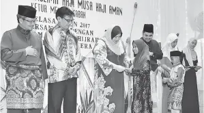  ??  ?? ROSNAH (tiga kiri) bersama Shahelmey (tiga kanan) dan Amrullah (kiri) menyampaik­an duit raya kepada anak-anak yatim dan asnaf.