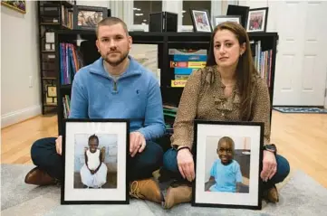  ?? CLIFF OWEN/AP ?? Bryan and Julie Hanlon show images of their adopted Haitian children, Gina, left, and Peterson last week in a play area at their home in Washington. They fear they won’t be able to secure the children’s passports and fly them out of Haiti.