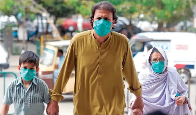  ?? Agence France-presse ?? ↑
A family, wearing face masks, arrives at the railway station in Karachi on Sunday.