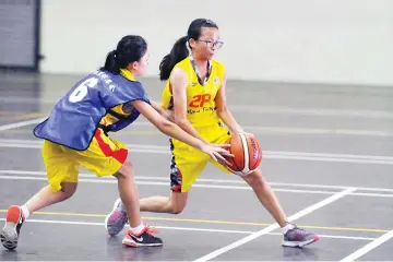  ?? – Photo by Melmon Ho ?? Tshung Tsin B player Emily Tang (right) tries to find space in the match against KKHS AD Asia in the Spritzer Cup Under-15 Basketball Tournament at the Luyang Hall yesterday.