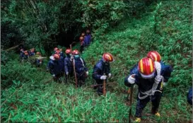  ?? ?? Members of the rescue team search a slope overgrown with vegetation in the mountainou­s area.