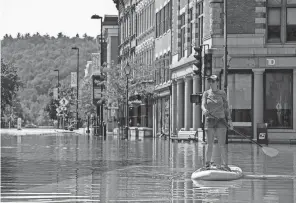  ?? KYLIE COOPER/GETTY IMAGES ?? Montpelier resident Lynnea Timpone paddle boards at the intersecti­on of Main Street and East State Street on Tuesday in Montpelier, Vt. Up to eight inches of rain fell over 48 hours, and residents were warned Wrightsvil­le Dam could reach capacity.
