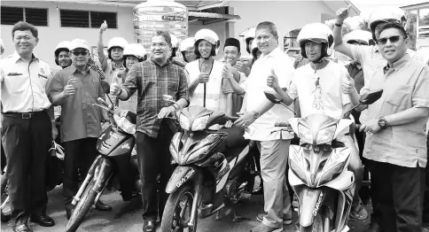  ??  ?? Saripuddin (front, third right) and Azharuddin (right), together with (front, from left) Baharin, Rosli and Wan Ahmad Uzir in a group photo with 20 motorcycli­sts who received their Sirim-certified helmets.