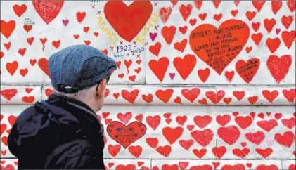  ?? Frank Augstein The Associated Press ?? A man walks past the National COVID Memorial Wall on the Thames Embankment in London on Thursday.