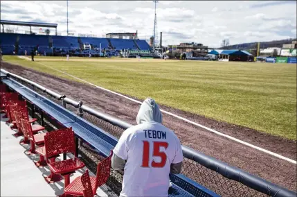  ?? PHOTOS BY BRETT CARLSEN / THE NEW YORK TIMES ?? A fan watches a Rumble Ponies game while wearing a Tim Tebow shirt earlier this season. What has become known as the Tebow effect — the economic benefits generated by his celebrity — comes at a fortunate time for Binghamton, N.Y.