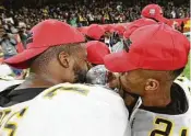  ??  ?? Grambling State’s Trent Scott, left, and Tyler Oliver kiss the Southweste­rn Athletic Conference championsh­ip trophy after the win over Alcorn State.
