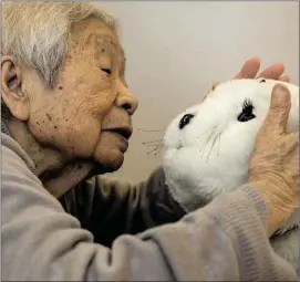  ??  ?? An elderly woman with dementia with Paro, the robot baby seal