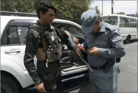  ?? AP PHOTO/RAHMAT GUL, FILE ?? FILE - An Afghan policeman checks the documentat­ion of a gun owner, at a temporary checkpoint in Kabul, Afghanista­n, July 4, 2021. A new report says decisions by Presidents Donald Trump and Joe Biden to pull all U.S. troops out of Afghanista­n were the key factors in the collapse of that nation’s military, leading to the Taliban takeover last year.