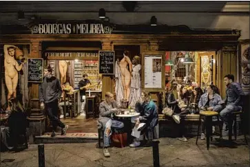  ?? PHOTOGRAPH­S BY BERNAT ARMANGUE Associated Press ?? TOURISTS and locals imbibe at a bar on Friday in downtown Madrid, where drinking establishm­ents, restaurant­s, museums and theaters are open, even though COVID-19 outbreaks have strained hospitals.