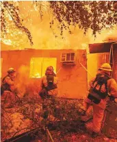  ?? AFP ?? Firefighte­rs push down a wall while battling against a burning apartment complex.