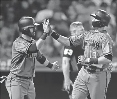  ??  ?? The Diamondbac­ks' Nick Ahmed, right, and Daniel Descalso celebrate after they scored on a double hit by Jeff Mathis during the fourth inning of a baseball game against the Angels on Monday.