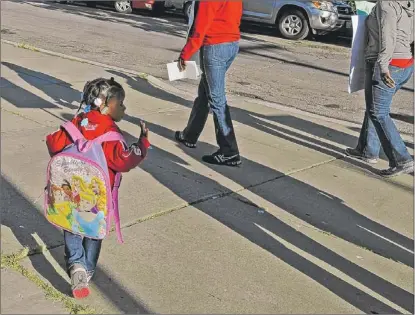  ??  ?? A little girl waves to striking teachers at Hefferan Elementary on Monday.
| JOHN H. WHITE~SUN-TIMES