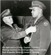  ??  ?? His right arm in a sling, Captain Charles L. Thomas receives the Distinguis­hed Service Cross from Brigadier General Joseph E. Bastion