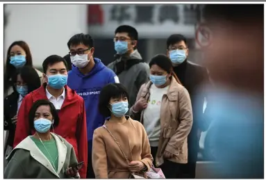  ?? (AP/Andy Wong) ?? Commuters wearing face coverings to help curb the spread of the coronaviru­s exit a subway station during the morning rush hour today in Beijing.