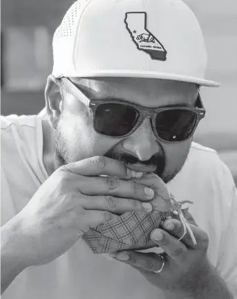  ?? DANIEL A. VARELA dvarela@miamiheral­d.com ?? Atlanta native Kevin Johnson, 33, takes a bite out of a burger during South Beach Wine & Food Festival’s Burger Bash on Feb. 25.