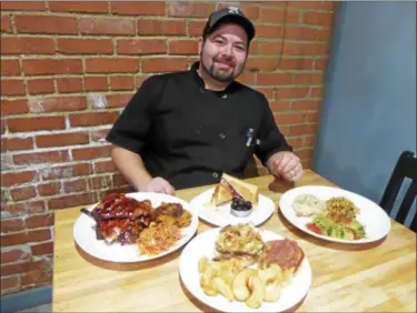  ?? JANET PODOLAK — THE NEWS-HERALD ?? Brad Reinhard shows off some of his dishes for Mentor’s Fourk at Matchworks, where he is the new executive chef. Clockwise from left are the slow-roasted baby-back ribs with a Chardon maple glaze, carrot slaw and sweet potato casserole; sweet and smoky...