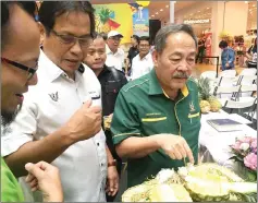  ??  ?? (From right) Sagah and Dr Abdul Rahman sample some of the pineapples on display at the exhibition booths.