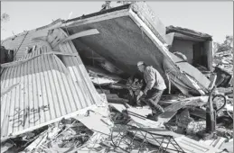  ?? By Mike Hutmacher, AP ?? Tornado survivors: Richard Keith helps sister-in-law Mitzi Keith on Monday in Wichita. There were at least 120 reports of Midwest tornadoes this weekend, primarily in Kansas.