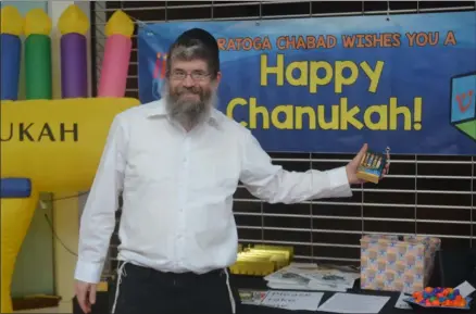  ?? LAUREN HALLIGAN - MEDIANEWS GROUP ?? Rabbi Abba Rubin of Saratoga Chabad stands by a Chanukah display at Wilton Mall.